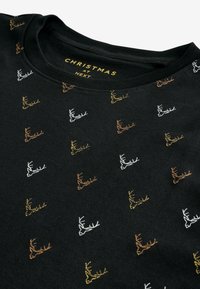 Sort sweatshirt med et gentaget mønster af stiliserede rensdyr i hvid, guld og brun broderi, med en rund halsudskæring.
