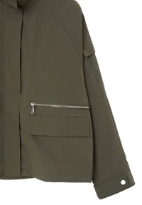 Manche de veste vert olive et bas avant avec une poche zippée horizontale en argent, une poche à rabat et un détail de poignet boutonné.