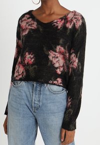 Maglione nero corto con motivo floreale in rosa e verde, scollo a V e maniche lunghe, realizzato in tessuto strutturato.