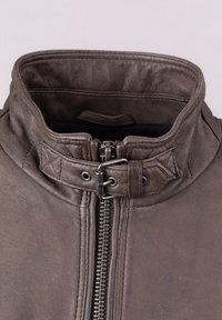 Brown leather jacket with a high collar, featuring a silver zipper and quilted accents. The leather has a smooth texture and matte finish.