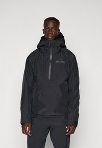 Svart vattentät jacka med dragkedja i halsen, justerbar huva och kardborreband vid ärmarna. Har en slim fit och är tillverkad av ett lätt, slitstarkt material.
