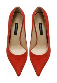 Zapatos de tacón alto de ante rojo con punta afilada y un forro interior suave. Etiqueta de la marca "NINE WEST" visible en las plantillas.