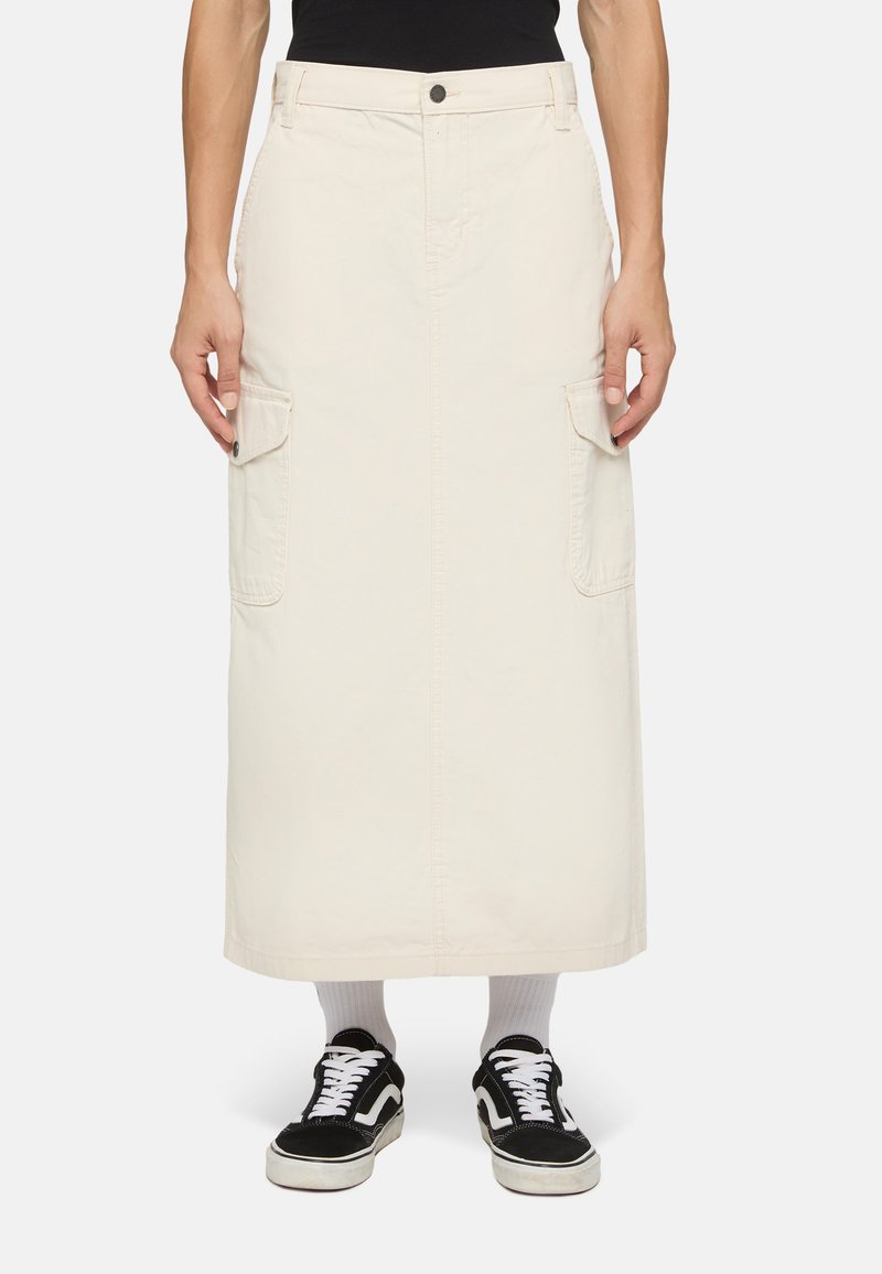 Beige cargo kjol med rak silhuett, med sidofickor och knappstängning, ihop med svarta sneakers och vita strumpor.