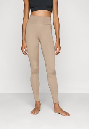 Høyt liv, beige tights laget av elastisk materiale, med en glatt tekstur og en tettsittende fasong som komplementerer kroppen.