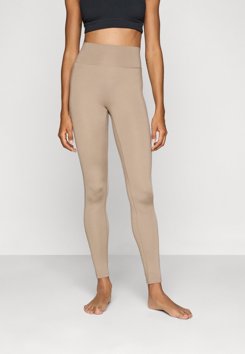 Høyt liv, beige tights laget av elastisk materiale, med en glatt tekstur og en tettsittende fasong som komplementerer kroppen.