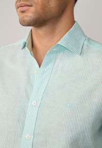 Lichtblauw en wit gestreept heren overhemd van katoen, met een button-down kraag en een klein geborduurd logo op de borst.