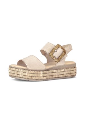 Beige platform sandal with woven textured sole, open toe, wide straps, and decorative large square buckle on ankle strap.