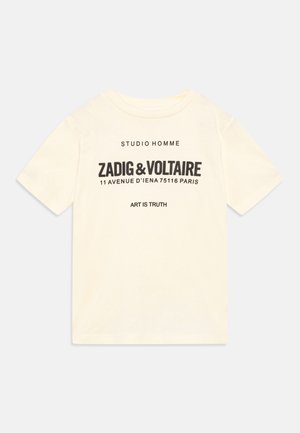 T-shirt en coton crème avec des manches courtes, col rond, texte imprimé noir et détails de logo sur le devant.