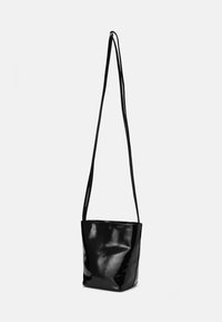 Svart lackad läder tote-väska med en glänsande yta, som har två långa axelremmar och en enkel, odekorerad design.