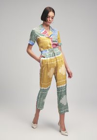 Conjunto de dos piezas que incluye una camisa de manga corta con cuello en colores de estampado paisley y pantalones con cintura elástica. El material parece ligero y suave.