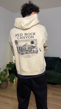 Cream hoodie featuring a graphic design of Red Rock Canyon, with text and a desert scene. Soft texture, relaxed fit, and a drawstring hood.