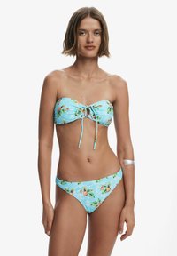 Pánt nélküli bikini szett világoskék háttérrel, élénk ananász és levélmintákkal. Elöl állítható megkötő rész.