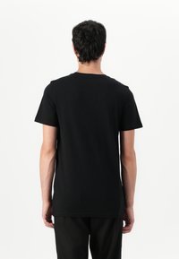 Tricou din bumbac negru cu guler clasic, mâneci scurte și o croială relaxată. Textură netedă, fără modele sau detalii vizibile.