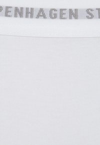 Weißer Stoff mit feiner gerippter Textur, der entlang der oberen Kante ein graues Etikett mit dem Aufdruck "Copenhagen Street" zeigt.