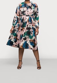 Middellange jurk met bloemenprint, voorzien van een elastische halslijn en manchetten. Heeft groene, blauwe, roze en zwarte kleuren, een getailleerde taille en een luchtige rok.