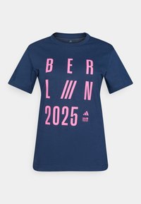 Marineblå bomulds t-shirt med stor pink tekst "BERLIN 2025" og grafiske detaljer. Rund halsudskæring og korte ærmer.