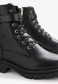 Bottes basses en cuir noir à lacets avec fermeture éclair latérale, bride de fermeture, œillets en métal et semelle crantée robuste.