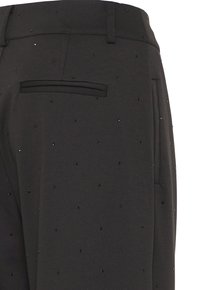 Pantaloni neri con piccole decorazioni nere, dotati di passanti per cintura e una tasca posteriore orizzontale.