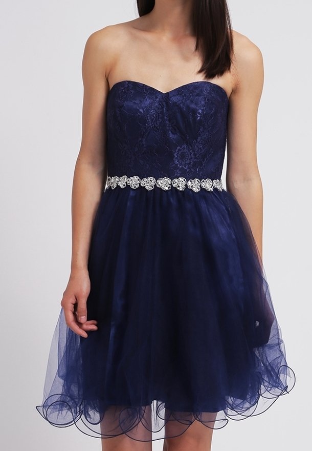 Robe bleu marine sans bretelles avec corsage en dentelle florale, ceinture argentée à motifs floraux et jupe en tulle à couches, portée par une femme aux cheveux noirs et raides.