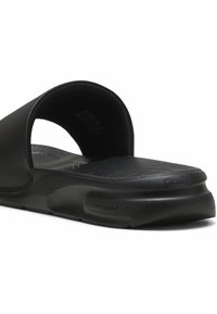 Sort slide sandal med en bred overdel og tekstureret fodseng, lavet af et fleksibelt materiale, suppleret med en robust sål.