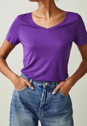 Paars T-shirt met korte mouwen en V-hals van glad materiaal, gecombineerd met een hooggetailleerde blauwe spijkerbroek met een klassieke pasvorm en zakdetails.