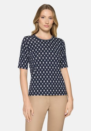Marineblaues Kurzarmoberteil mit weißem geometrischem Muster, rundem Ausschnitt und weicher Textur. Verfügt über ein figurbetontes Design.