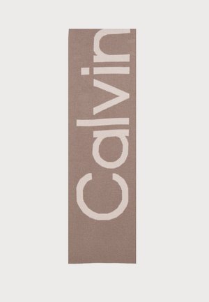 Tappeto con logo Calvin Klein, forma rettangolare, sfondo marrone chiaro, testo bianco in grassetto, texture morbida, design minimalista.