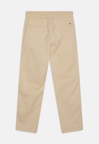 Beige katoenen broek met een elastische tailleband, voorzien van twee achterzakken en een klein logolabel vlakbij de tailleband.