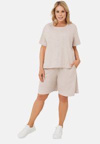 Jasnoszara, teksturowana koszulka z krótkim rękawem, w połączeniu z dopasowanymi szortami z kieszonką. Uzupełniona o białe trampki.
