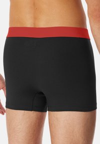 Sorte boxer shorts med en rød talje; lavet af strækstof, med et tætsiddende design og en sømløs ryg for komfort.