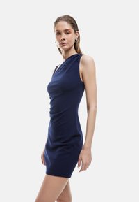 Marineblauwe, verloop-jurk met één schouder, gemaakt van rekbaar materiaal. Het heeft een aansluitend ontwerp en een zachte textuur. Bevat een zij-enkeleing voor extra accent.
