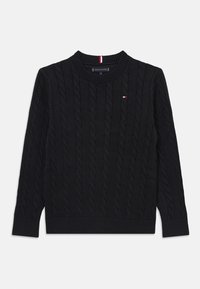 Pull en maille noire à col rond, avec des poignets et un ourlet côtelés, présentant un petit logo rouge, blanc et bleu sur la poitrine.