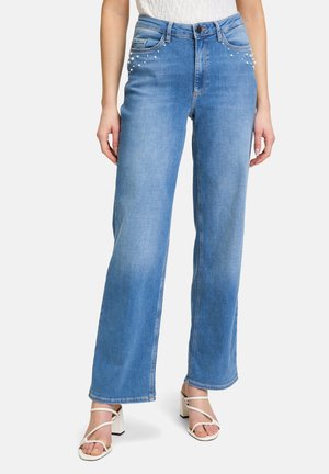 Hellblaue weit geschnittene Jeans mit dekorativen Perlenakzenten an den vorderen Taschen, hoher Taillenbund und klassischer Denim-Textur.