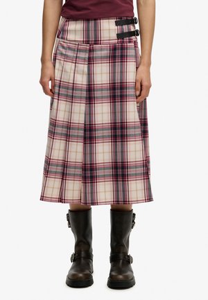 Falda plisada de longitud media con patrón de cuadros en rosa, rojo y gris, asegurada con dos hebillas negras, combinada con botas marrón oscuro con hebilla.