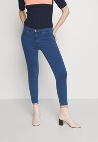 Blå skinny jeans med en klassisk design och fem fickor, kombinerat med ljusrosa ankelskor med klack.