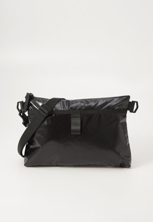 Bolsa de ombro em nylon preto com um design elegante, alça ajustável e fecho superior com zíper. Superfície texturizada com detalhes de hardware mínimos.