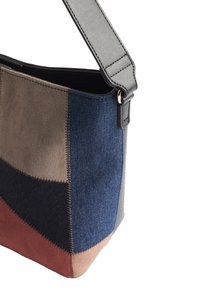 Mehrfarbige Handtasche mit Wildleder- und Denim-Elementen in Braun, Blau, Grau und Rost. Glatter Tragegurt und kontrastierendes Stichdetail.