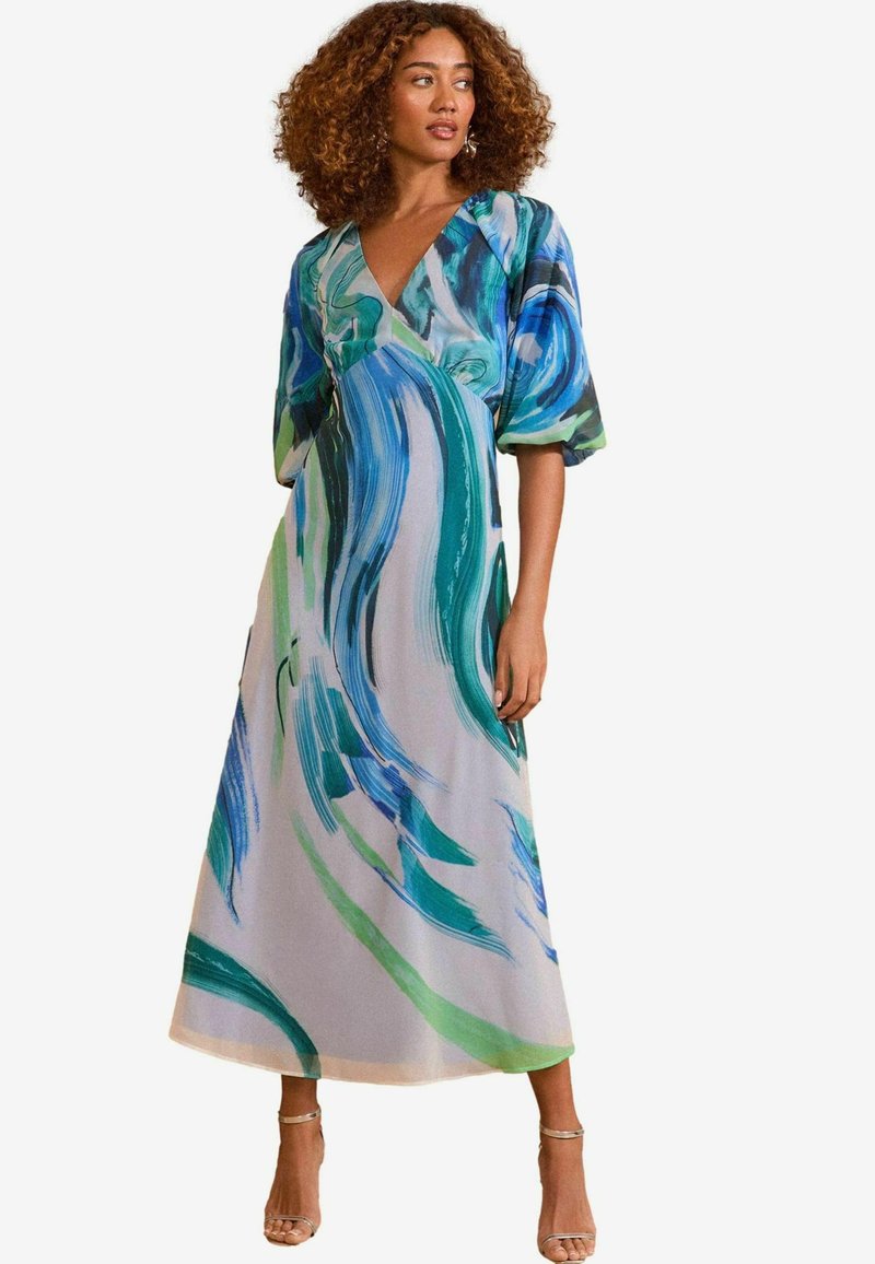 Maxi jurk met een V-hals, korte pofmouwen en een vloeiende silhouet, versierd met blauwe en groene abstracte patronen op een lichte achtergrond.