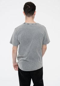 Gray cotton t-shirt with a crew neckline, short sleeves, and a relaxed fit. Features a faded, textured appearance. No visible graphics or patterns.