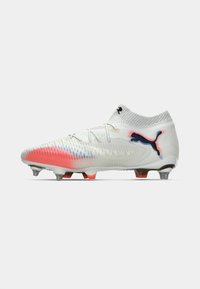 White Puma soccer cleat with red and blue accents, textured upper, lace closure, and metal studs on the sole for firm ground.
