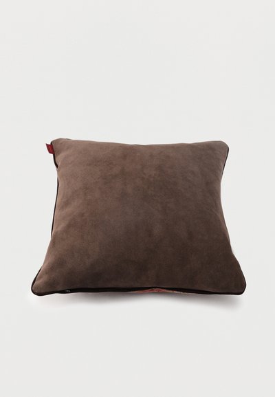 Coussin rectangulaire marron avec une texture douce semblable à du daim, coins légèrement arrondis, et une petite étiquette en tissu rouge sur un côté.
