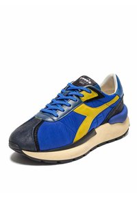 Scarpa sportiva blu e gialla con un mix di pelle e tessuto. Presenta un colletto imbottito, accenti testurizzati e una suola intermedia spessa e bianca.