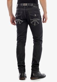 Schwarze Jeans im Slim-Fit-Stil mit kontrastierendem grauem Nähten, einzigartigen Taschen-Designs und einem Logo auf der Gesäßtasche. Strukturierten Stoff.