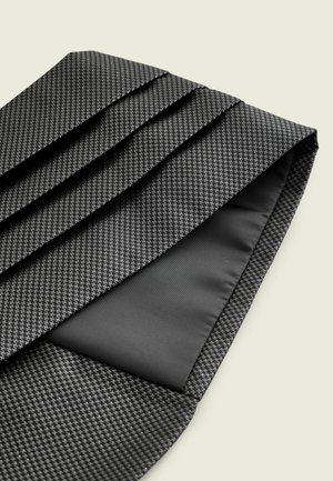 Juodas tekstūruotas kaklaraištis su šuns danties raštu ir klostėmis. Apatinė pusė yra lygi juoda medžiaga, rodanti kontrastingą dizaino elementą.