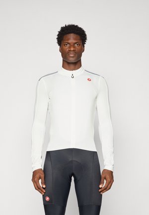 Langarm-Radsporttrikot in Weiß mit hohem Kragen, durchgehendem Reißverschluss und reflektierenden Akzenten an den Schultern. Schwarze Radsportshorts mit Polsterung.