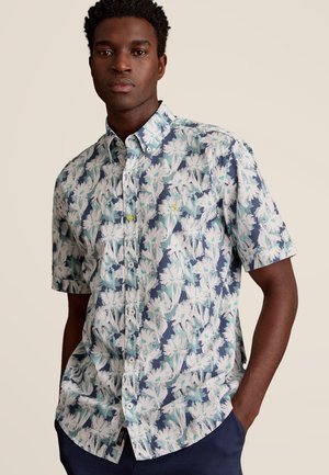 Kortärmige button-up shirt met een wit en blauw bloemenpatroon op een marineblauwe achtergrond. Heeft een kraag en een klein logo op de borst.