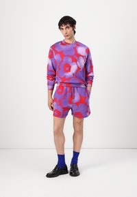 Fialové sweatshirty so vzorom kvetov a šortky v živej červenej farbe, vyrobené z bavlny. V kombinácii s modrými ponožkami a čiernymi topánkami. Jednoduchý dizajn.