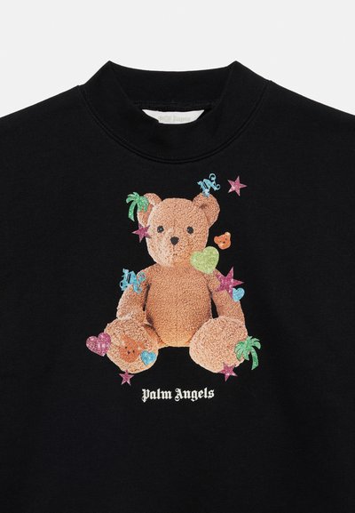 Μαύρο πουκάμισο με ένα υφασμάτινο αρκουδάκι μέσα σε πολύχρωμα αστέρια, καρδιές, φοίνικες και το κείμενο "Palm Angels" κάτω από το αρκουδάκι.