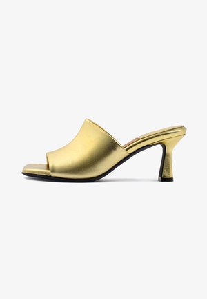 Metallisch goldene Offen-toe-Mules mit einer glatten Textur, geschwungenem Oberdesign und einem schlanken, konischen Absatz. Akzentdetails an der schwarzen Sohle.