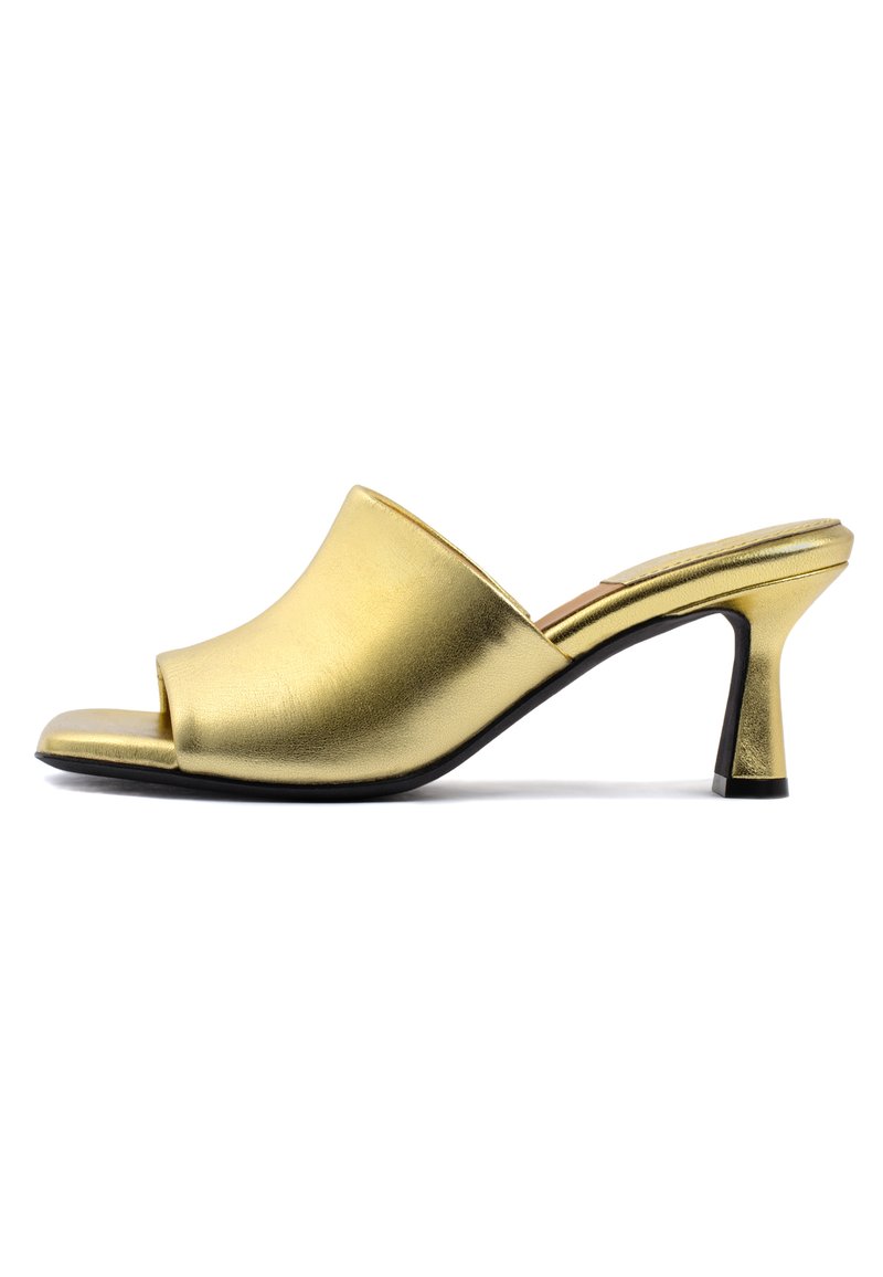 Mule aperti in metallo dorato con texture liscia, design della parte superiore curvato e tacco conico sottile. Dettaglio di accentuata suola nera.